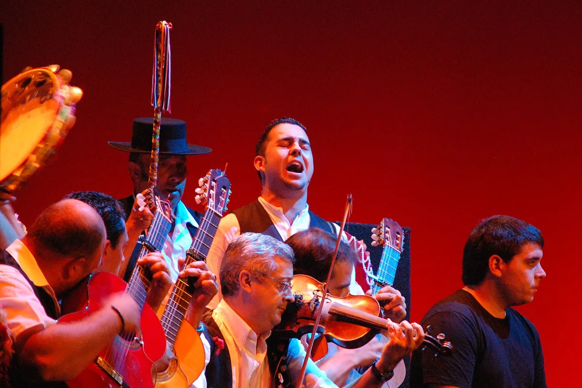 A verdiales group on a stage with a red backdrop: a singer with his head back, guitars, a violin and a tambourine